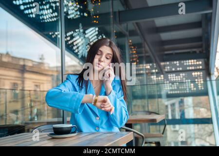 Femme en attente d'un ami qui est en retard pour le rendez-vous. Gros plan portrait vue de tête bouleversée jeune belle femme d'affaires attrayant vérifier le temps o Banque D'Images