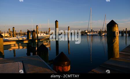 Petit matin lumière sur le petit port de Cambridge Maryland, avec des réflexions des pairs et des bateaux dans l'eau. Banque D'Images