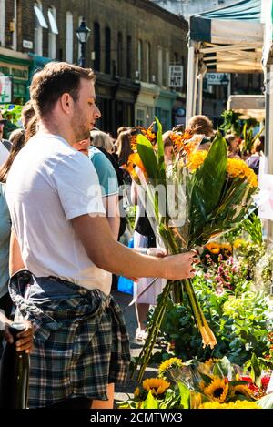 London, Royaume-Uni - 13 septembre 2020 : marché du dimanche des fleurs de Columbia Road. Les gens choisissent des fleurs Banque D'Images