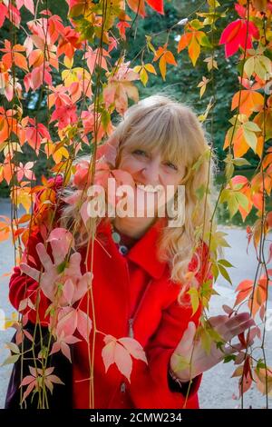 Femme souriante, feuilles d'automne, jardin botanique VanDusen, Vancouver, Colombie-Britannique, Canada. Banque D'Images