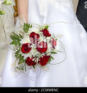 Bouquet de roses rouges dans sa main jusqu'à la mariée Banque D'Images