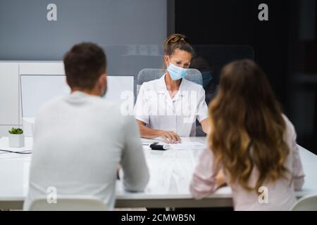 Médecin parlant au patient lors de la réunion au sujet de la grossesse avec le visage Masques Banque D'Images