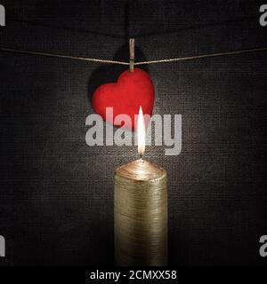 Bougie brûlante et papier rouge cœur sur une corde sur fonds sombres en relief vintage Banque D'Images