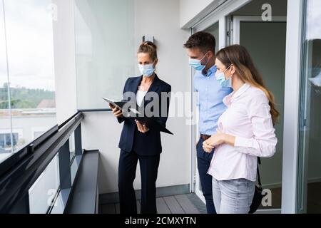 Couple heureux achetant une nouvelle maison avec Realtor portant des masques de visage Banque D'Images