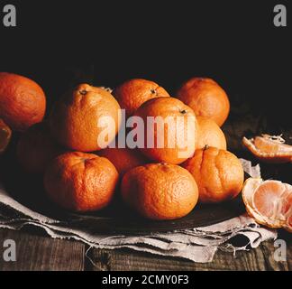 tas de mandarine orange mûre ronde non pelée sur un gris serviette en lin Banque D'Images