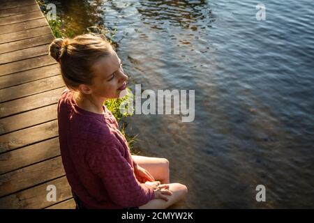 Femme assise au quai, en regardant le lac Kabetogama dans le parc national des voyageurs, Minnesota Banque D'Images