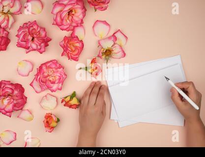la main femelle tient un stylo blanc sur une feuille blanche vide de papier Banque D'Images