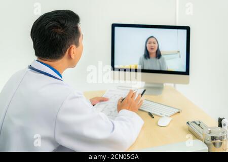 Le médecin asiatique porte un manteau blanc et un casque parlant la vidéoconférence sur ordinateur portable à l'aide de l'application de consultation d'appel vidéo en ligne. Médical à distance h Banque D'Images