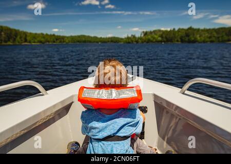 Garçon à cheval sur l'arc d'un bateau sur le lac Kabetogama dans le parc national des voyageurs, Minnesota Banque D'Images