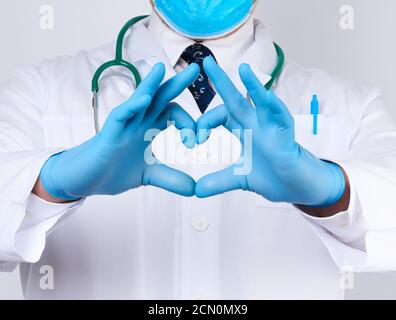 adulte médecin homme dans un manteau médical blanc avec un le stéthoscope sur son cou montre un geste de coeur avec h Banque D'Images