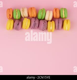 gâteaux de macarons ronds jaunes et violets sur fond rose, dessert à la suite Banque D'Images