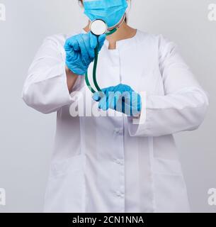 femme medic sous un manteau et un masque blancs, portant des gants en latex médical bleus Banque D'Images