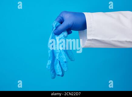 la main mâle tient une paire de gants médicaux en latex sur fond bleu Banque D'Images