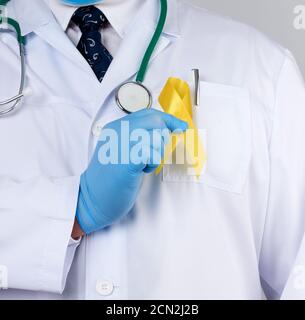 porte-gants en latex blanc uniforme et stérile un ruban jaune dans sa main Banque D'Images