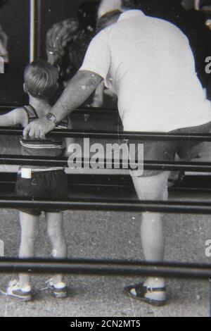 Belle photographie en noir et blanc vintage des années 1970 d'un père aidant son fils. Banque D'Images