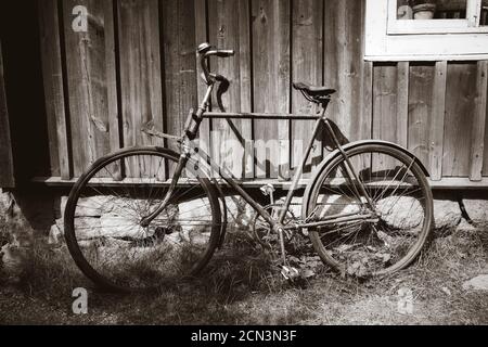 Vieux vélo sur un mur en bois. Photographie en noir et blanc Banque D'Images