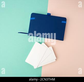 pile de cartes de visite rectangulaires blanches vierges et bloc-notes bleu sur fond vert beige Banque D'Images