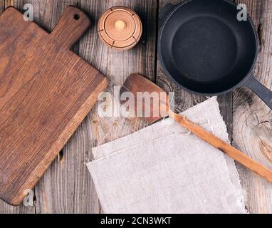 vider la poêle en fonte ronde noire avec poignée, planche à découper en bois et couteau sur une table grise Banque D'Images