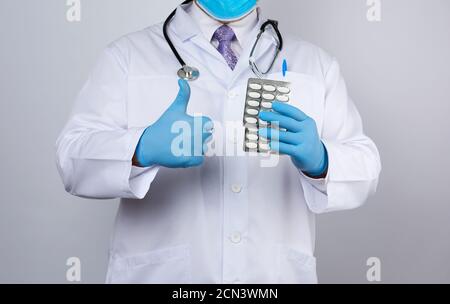 le médecin thérapeute est vêtu d'un manteau blanc uniforme et des gants stériles bleus sont debout et tiennent Banque D'Images