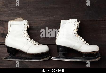 paire de patins en cuir blanc pour le patinage artistique sur un arrière-plan en bois marron Banque D'Images