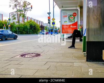 Moscou. Russie. 4 septembre 2020 jambes d'un homme assis sur un banc à un arrêt de transport en commun. Attente de l'arrivée du bus. Jour d'été. Élevée Banque D'Images