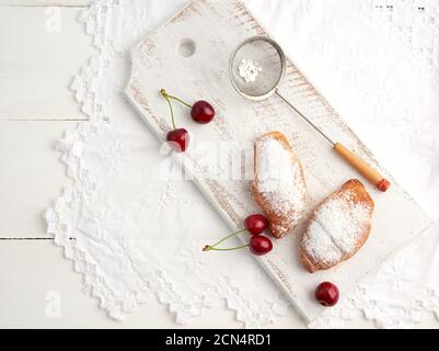 deux croissants frais saupoudrés de sucre glace sur un blanc planche en bois Banque D'Images