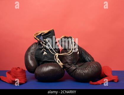 gants de boxe vintage en cuir marron sur fond rouge, équipement de sport Banque D'Images