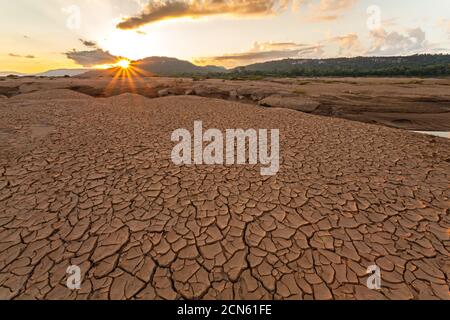 Terre fissurée près de l'eau de séchage au crépuscule à Sam Pan Bok dans le Mékong. Province d'Ubonratchathani, Thaïlande Banque D'Images