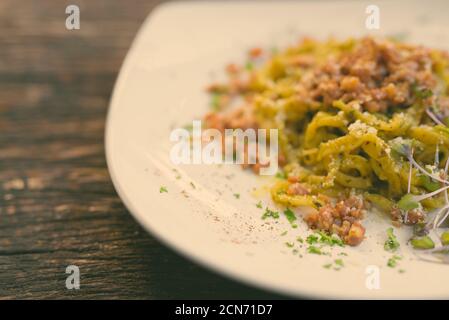Tagliolini pâtes avec pesto et saucisse contre table en bois Banque D'Images