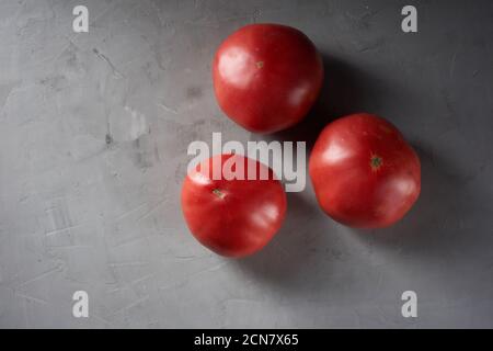 trois tomates rouges mûres sur fond gris, vue du dessus Banque D'Images