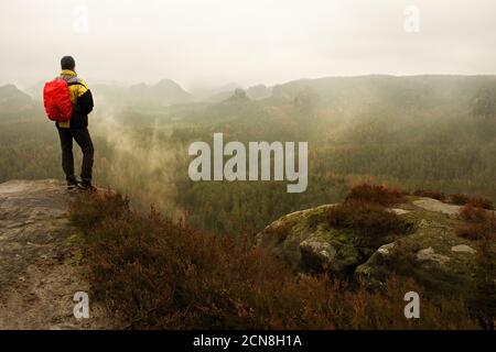 Touriste avec sac à dos prend des photos avec un smartphone de la pluie vally. Vallée féoggy rêveuse en contrebas Banque D'Images