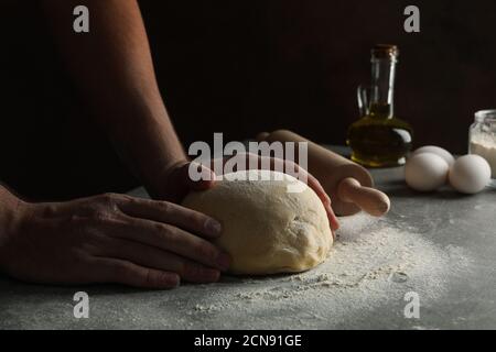 Homme cuisant de la pâte sur une table grise, gros plan Banque D'Images