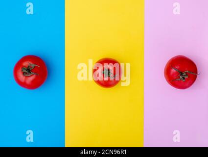 Image créative de trois tomates sur fond clair. Plats à plat Banque D'Images