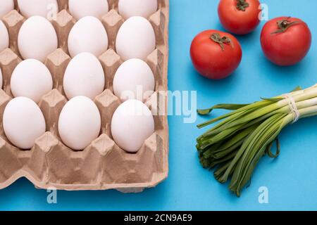 Œufs, oignon vert, tomates. Ingrédients pour la cuisson de l'omelette sur une table bleue, vue du dessus Banque D'Images