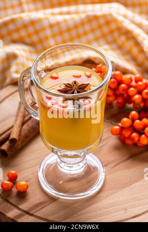 Thé d'argousier chaud au sucre brun, cannelle, carnation dans une tasse de verre sur fond de bois - image Banque D'Images