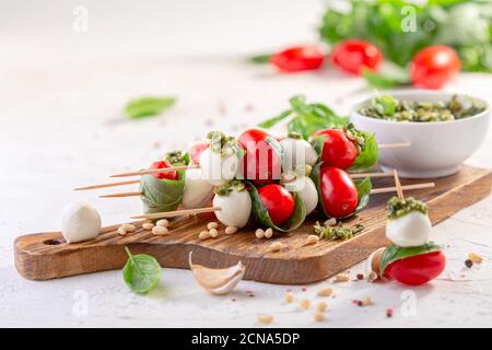 Salade Caprese sur brochettes avec sauce pesto. Banque D'Images