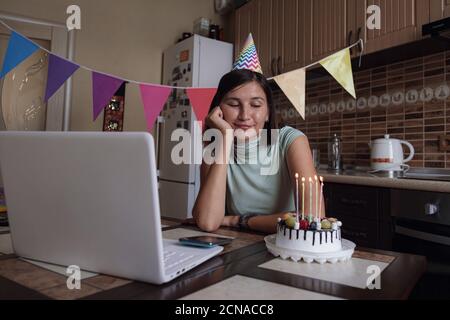 femme célébrant son anniversaire en ligne en période de quarantaine. Femme célébrant son anniversaire par le biais d'une fête virtuelle par vidéoconférence avec des amis. Décoration authentique Banque D'Images