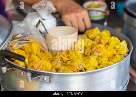 Des momos vapeur traditionnels dans un cuiseur vapeur en bambou avec sauce tomate sur le marché de la cuisine de la rue à Thiland. Banque D'Images