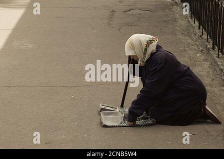 Chernihiv, Ukraine, 7 juin 2019. Une femme âgée dans un foulard supplie pour de l'argent, s'agenouillant dans une rue de ville. Banque D'Images