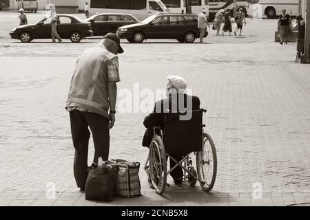 Chernihiv, Ukraine, 7 juin 2019. Un employé de la gare communique avec un homme âgé en fauteuil roulant. Assistance aux passagers souffrant de handicap Banque D'Images