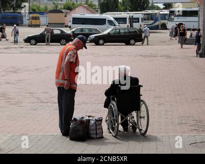 Chernihiv, Ukraine, 7 juin 2019. Un employé de la gare communique avec un homme âgé en fauteuil roulant. Assistance aux passagers souffrant de handicap Banque D'Images