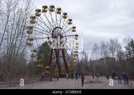 Pripyat, Ukraine, 14 mars 2020. Touristes près de la célèbre grande roue dans un parc d'attractions abandonné à Pripyat. Temps nuageux, le ciel est couvert Banque D'Images