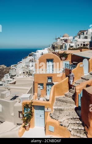 Santorini Grèce, jeune homme en vacances de luxe à l'île de Santorini regardant le lever du soleil près de l'église du dôme bleu et de la chaux Banque D'Images