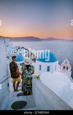 Santorini Grèce, jeune couple en vacances de luxe à l'île de Santorini regardant le lever du soleil à côté de l'église du dôme bleu et blanchir Banque D'Images