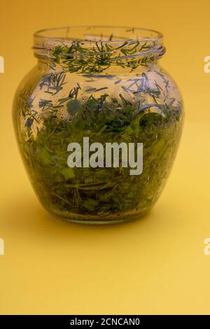 Herbes séchées dans un bol, épices sur papier jaune, verticales Banque D'Images