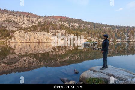 MAMMOTH LAKES, CALIFORNIE, ÉTATS-UNIS - 28 août 2020 : un randonneur se trouve à côté de la surface calme du lac Crystal, dans la région de Mammoth Lakes. Banque D'Images