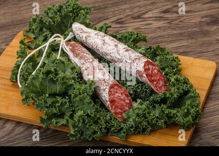 Saucisse de Fuet espagnole avec feuilles de salade sur fond de bois Banque D'Images