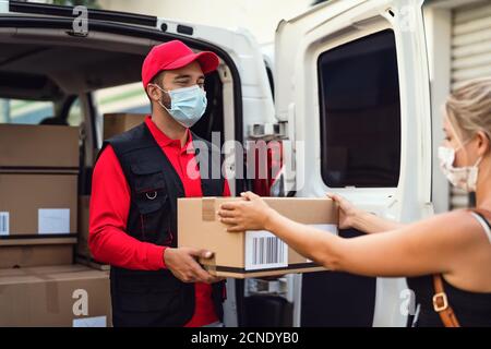 Accouchement homme portant un masque de protection du visage pour éviter le virus corona Propagation - livraison express de jeune coursier au client pendant le coronavirus épidémie Banque D'Images