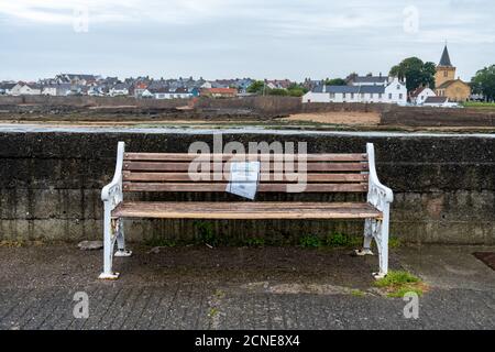 Un banc vide avec un signe d'avertissement de ne pas à Utilisation due au coronavirus dans une station balnéaire tranquille sur La côte est de l'Écosse Banque D'Images