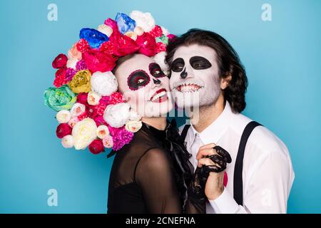 Photo de profil de mignon effrayant romantique couple homme dame tenir mains câliner joues beaming sourire porter noir robe mort costume bretelles à serre-tête roses Banque D'Images